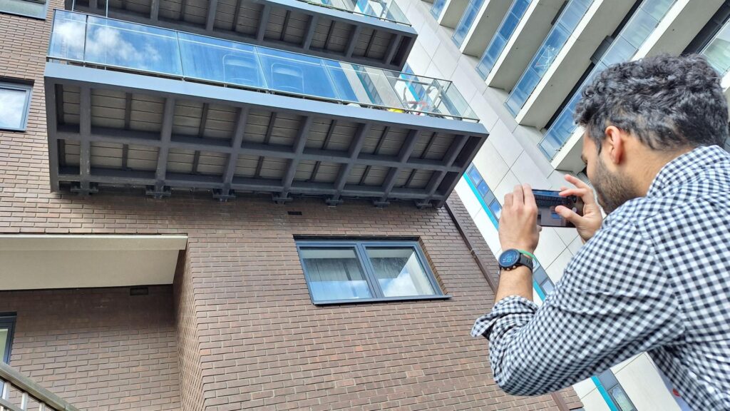 Person photographing modern building balcony.